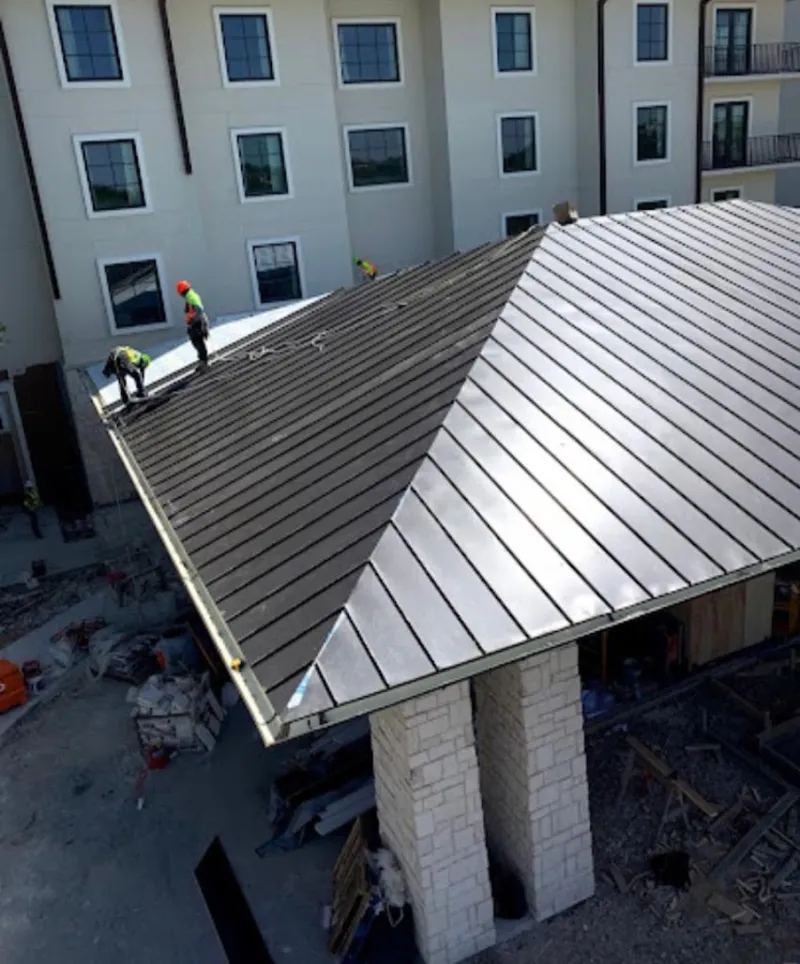 Crew installing standing seam metal roof panels on a commercial project in Lock Haven